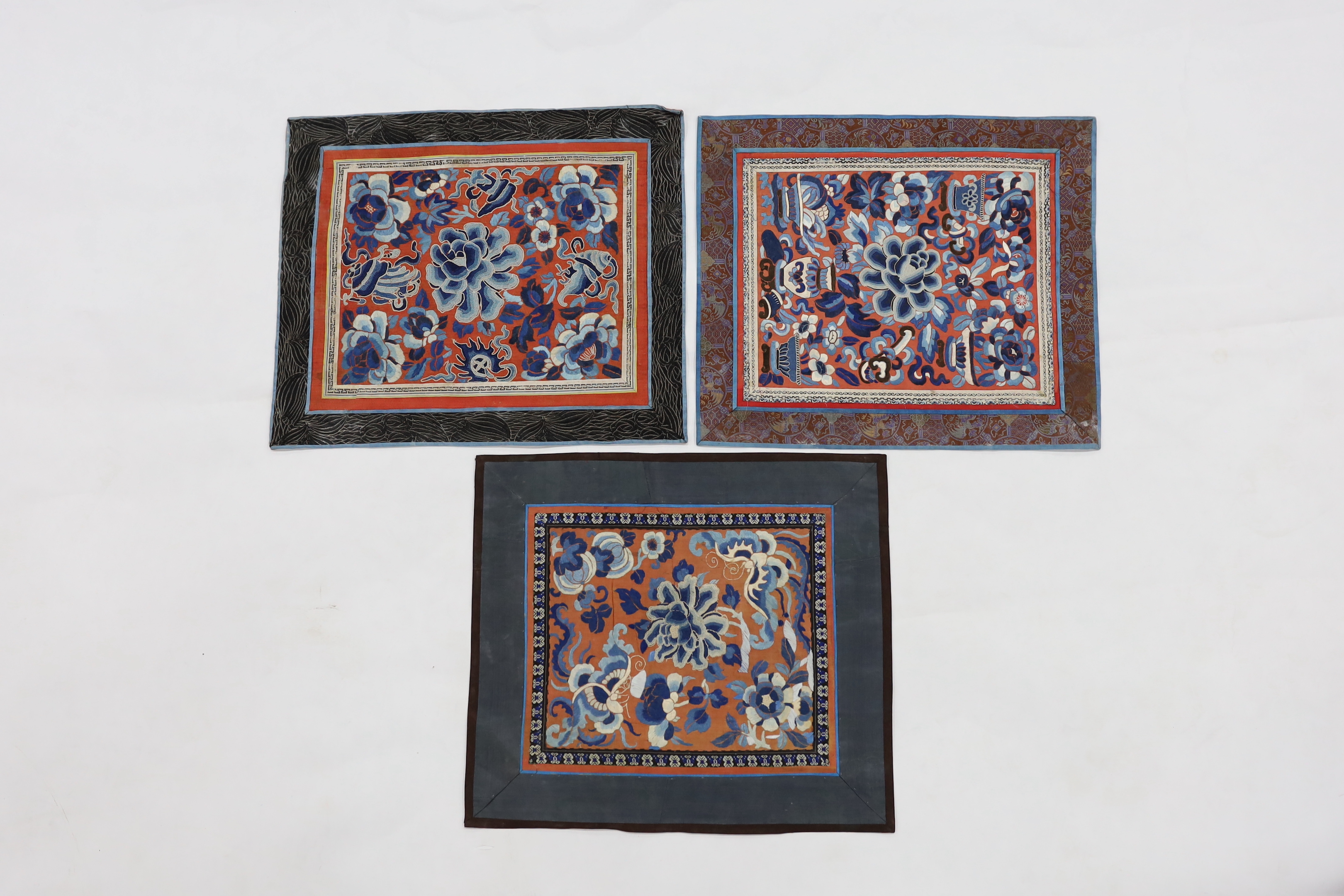 Five Chinese embroidered mats with polychrome silk embroidery using Beijing knot stitch, together with a large square blue silk cover with silk embroidered spot motifs and gold thread work, all items bordered with silk b